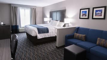 Una habitación de hotel con una cama, un sofá azul, un escritorio y dos cuadros en la pared.