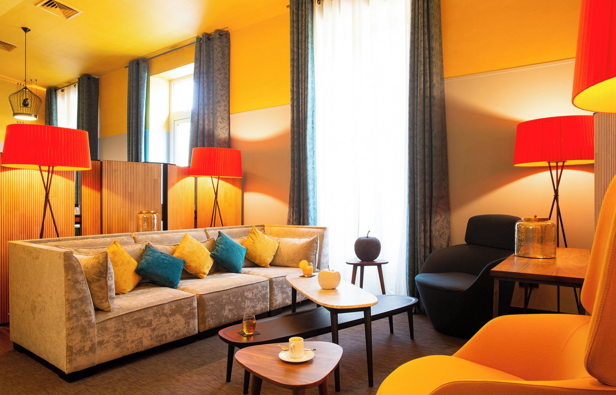 Ein Hotelzimmer mit einer Couch, Sesseln, einem kleinen Tisch und einer Lampe.