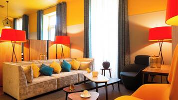 Ein Hotelzimmer mit einer Couch, Sesseln, einem kleinen Tisch und einer Lampe.