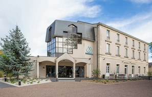 Ein Hotel mit modernem Design, das eine markante Eingangshalle mit überdachtem Bereich und einem großen Glasfenster zeigt.