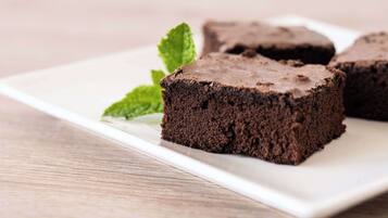 A white plate with three chocolate brownies and a mint leaf.
