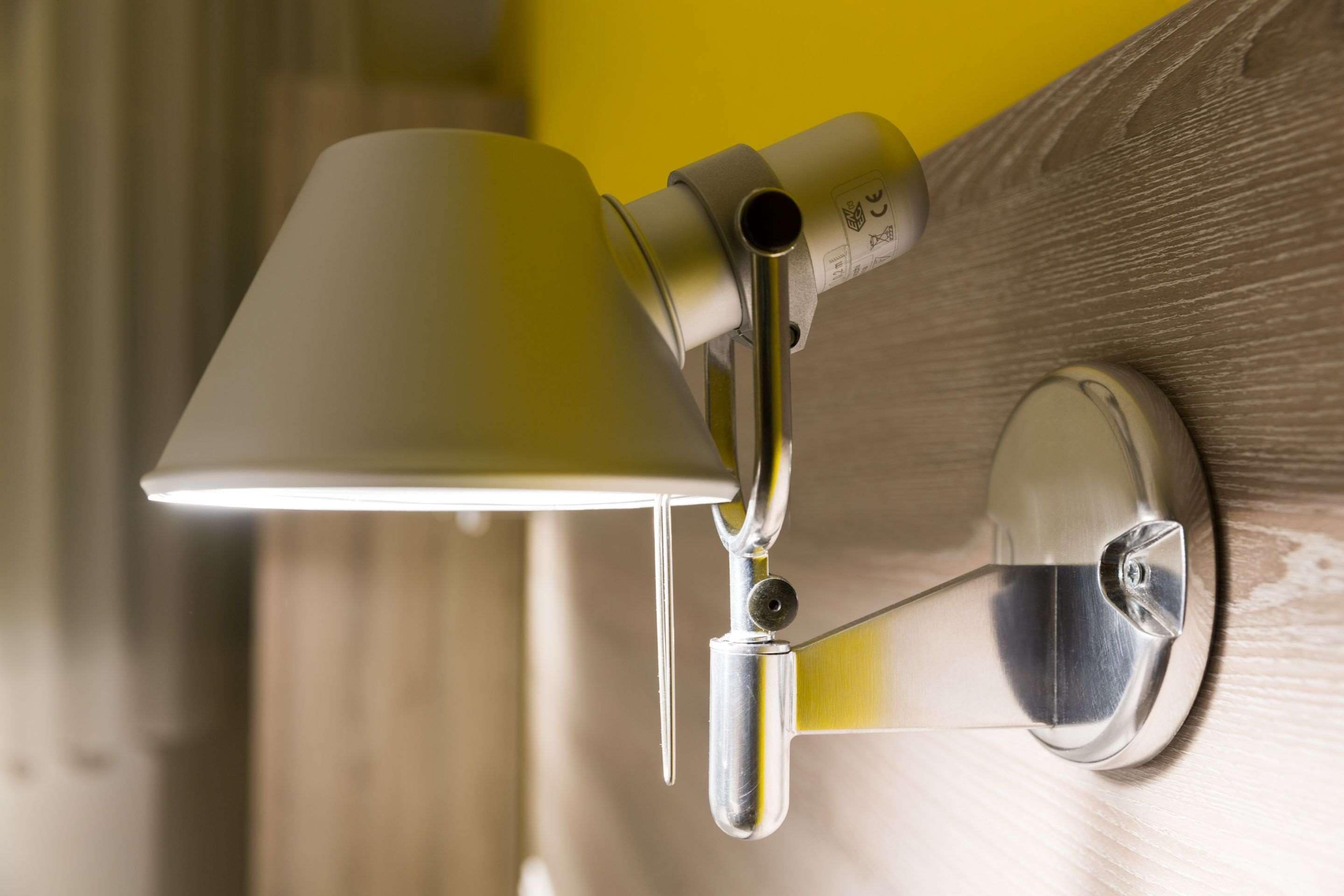 Une lampe murale avec un fini métallique et un abat-jour en verre transparent.