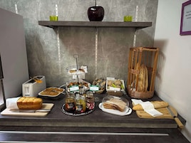 Un bufé de desayuno con panes, pasteles y mermeladas variadas.