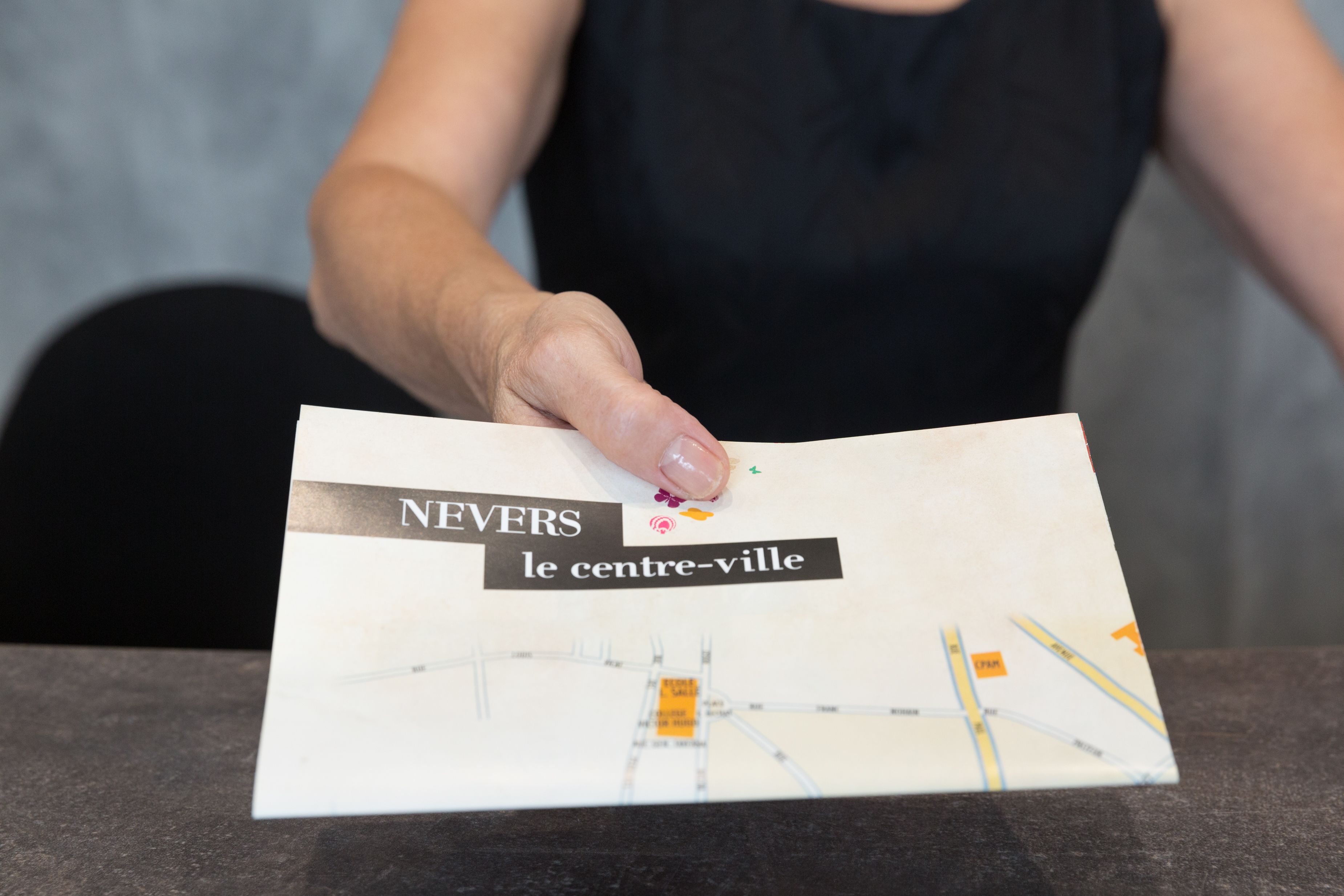 A hand holding a map with the text "NEVERS le centre-ville".