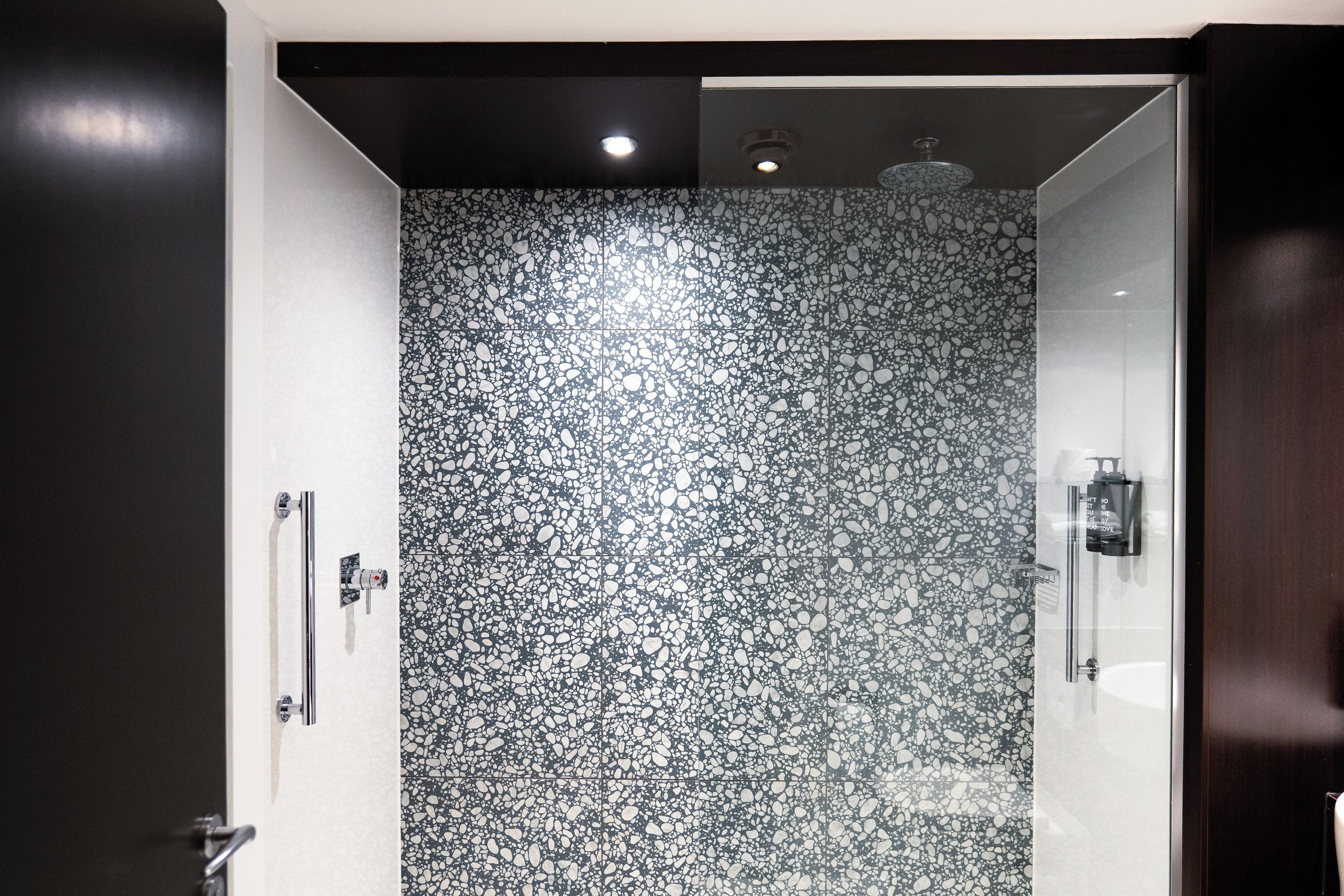 A bathroom with a terrazzo floor, a shower area, and a glass partition.