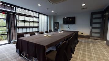 A conference room with a long table, chairs, a TV screen, and a door with frosted glass panels.