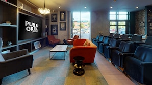 A pub and grill interior with seating, a TV screen, and a view of the outside. - Village Hotel Leeds South (Leeds)