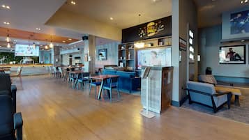 Et moderne pub- og grillmiljø med trægulve, blå siddepladser og et barområde.