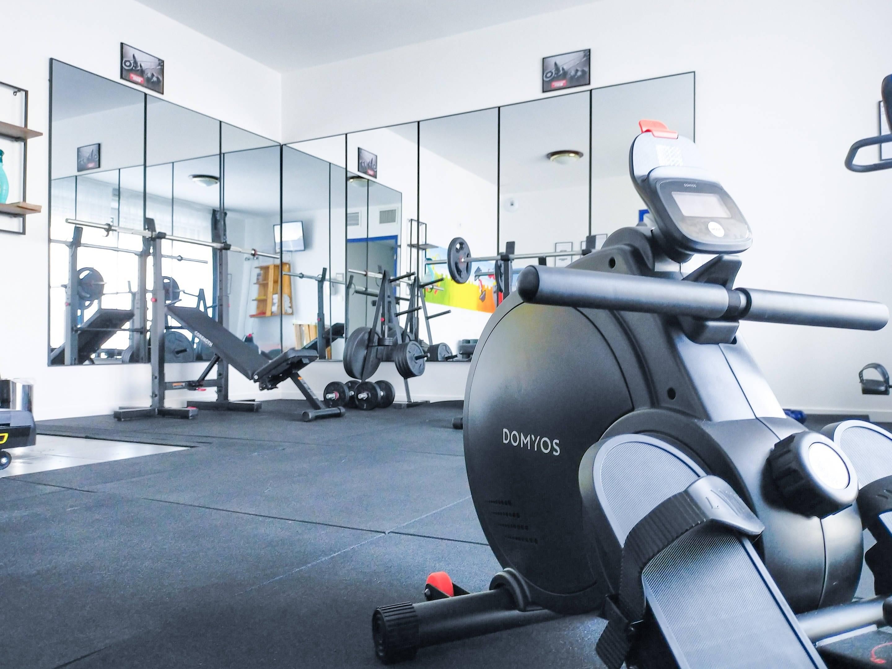 A gym with exercise equipment, a mirrored wall, and a weight rack.