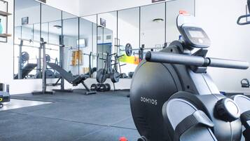 A gym with exercise equipment, a mirrored wall, and a weight rack.