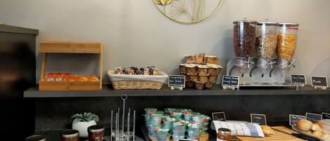 A breakfast buffet with various food options, including cereals, jams, and pastries.
