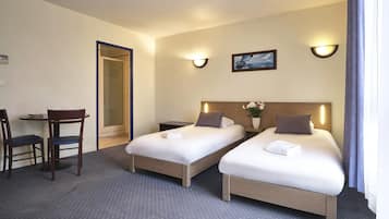 Una habitación de hotel con dos camas individuales, un escritorio pequeño con una silla y una mesita de noche.