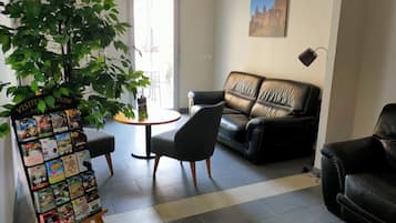 A modern living room with a black leather sofa, a round wooden table, and a potted plant.
