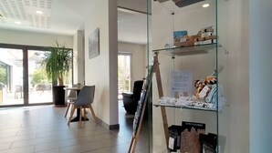 A reception area with a glass display case containing various items, a wooden easel, and a seating area with chairs and a table. - Comfort Aparthotel Carcassonne (Carcassonne)