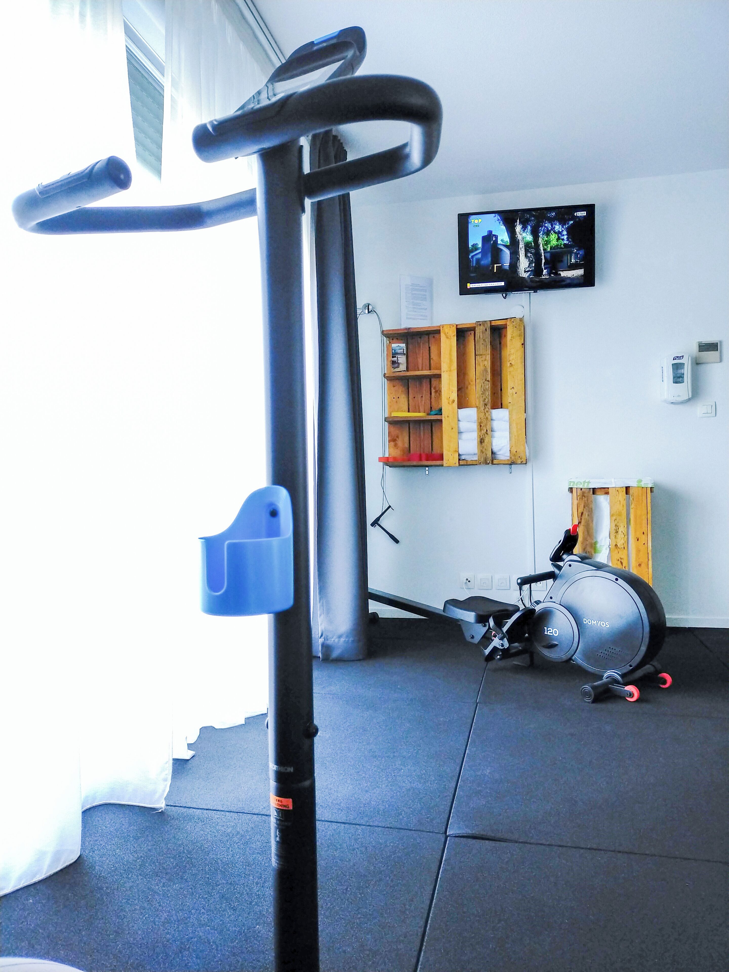 A gym with exercise equipment, a television, and a wooden shelf.