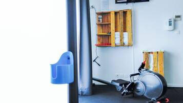 A gym with exercise equipment, a television, and a wooden shelf.