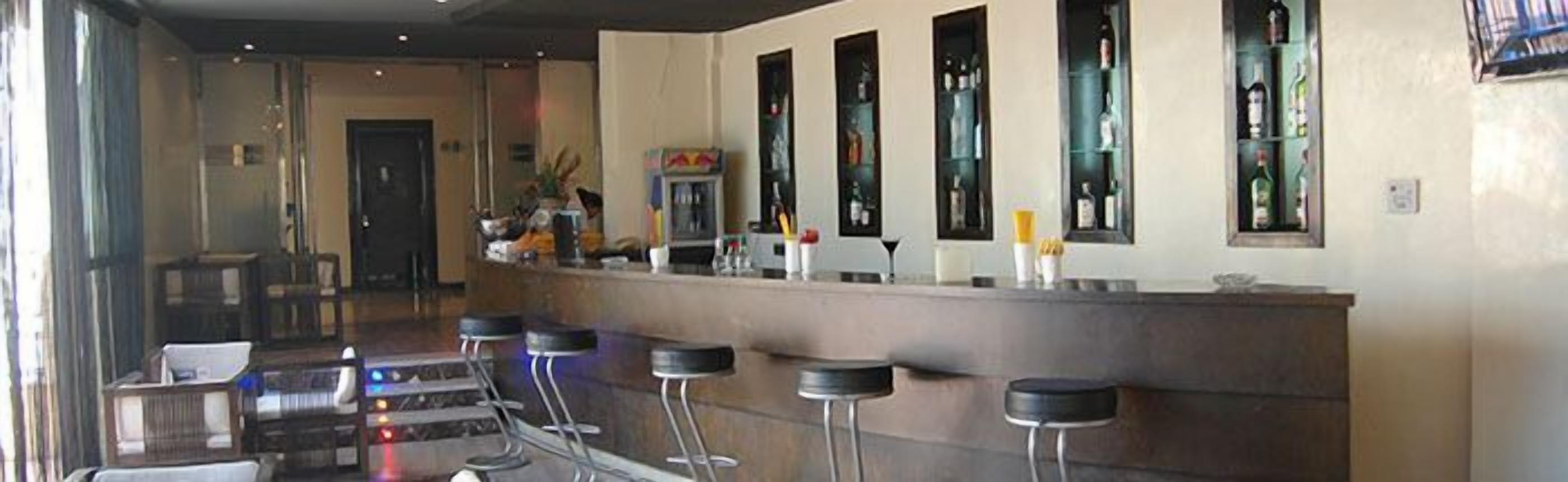 A bar area with a counter, stools, and a view of the street outside.