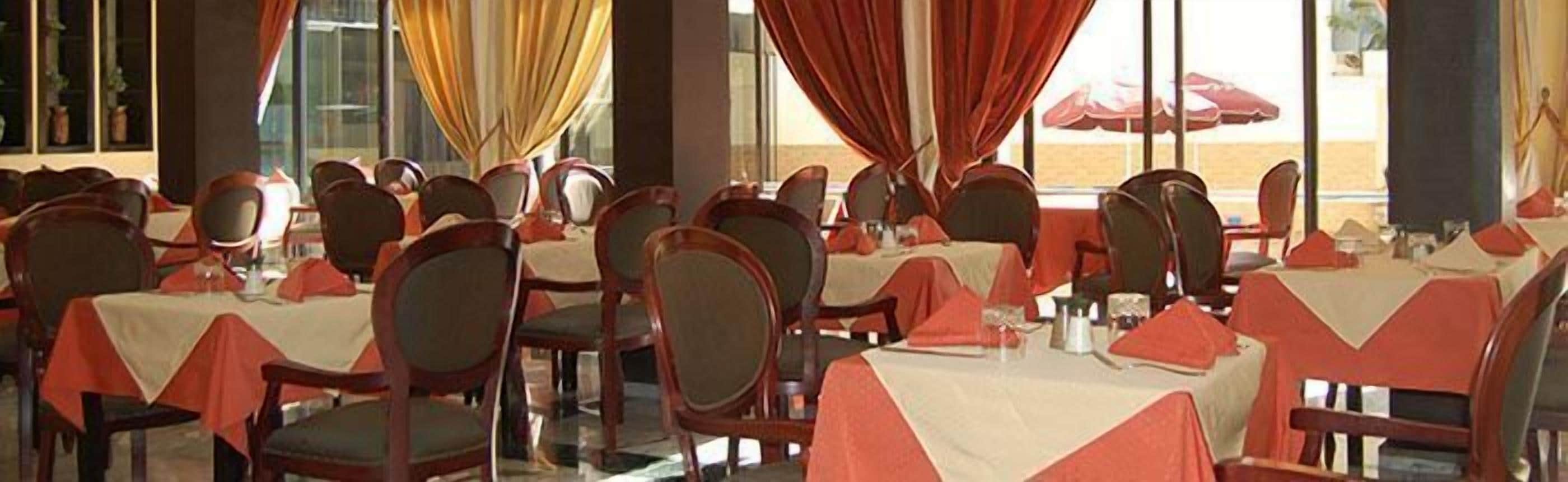 A restaurant with multiple tables and chairs, each covered with a tablecloth.