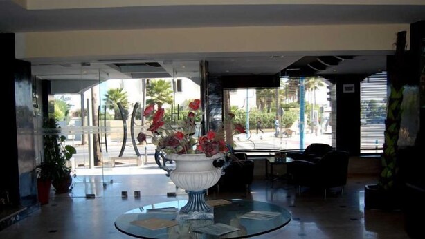 Eine Lobby mit Glastisch, Blumenvase und Blick auf die Straße.