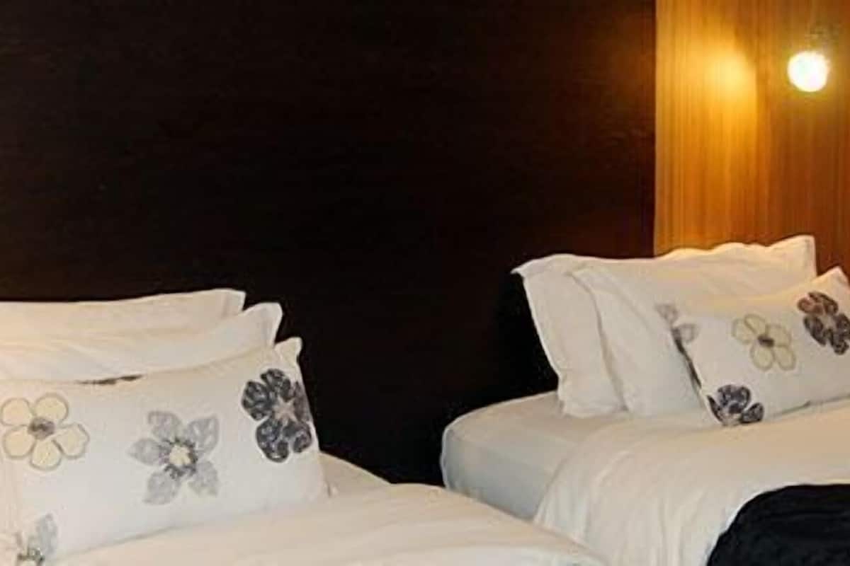 Ein Hotelzimmer mit zwei Betten, einer dunklen Wand und einer Leuchte.