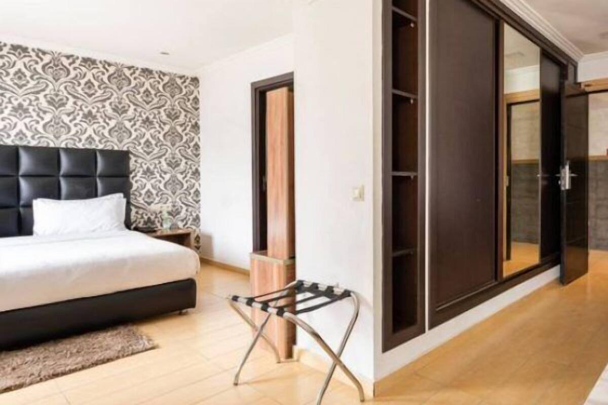 Ein modernes Schlafzimmer mit einem Bett, einem kleinen Hocker, einer Couch und einem Tisch mit Obst.