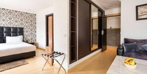Un dormitorio moderno con una cama, un taburete, un sofá y una mesa con fruta.
