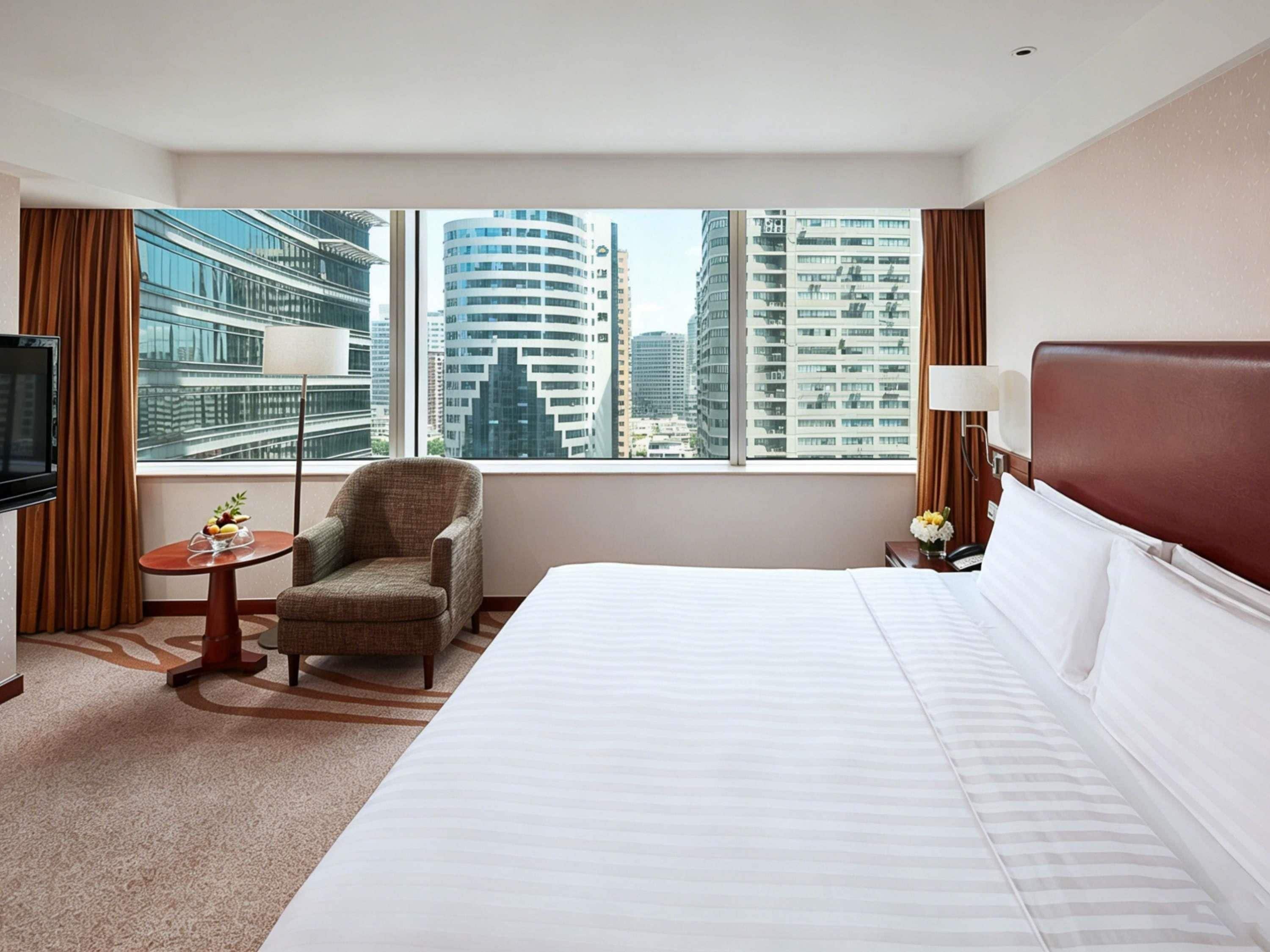 Une chambre d’hôtel avec un grand lit, une chaise, une petite table et un téléviseur.