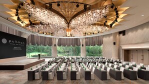 A conference room with rows of tables and chairs, a stage, and a large chandelier. - Pullman Shanghai Central-in XinTianDi & Yu Garden Area (Shanghai)