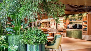 Espai interior modern amb diverses plantes, zones d'assaient i un taulell amb productes exposats.