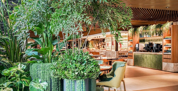Un espace intérieur moderne agrémenté de diverses plantes, de coins salon et d’un comptoir où sont exposés différents articles.