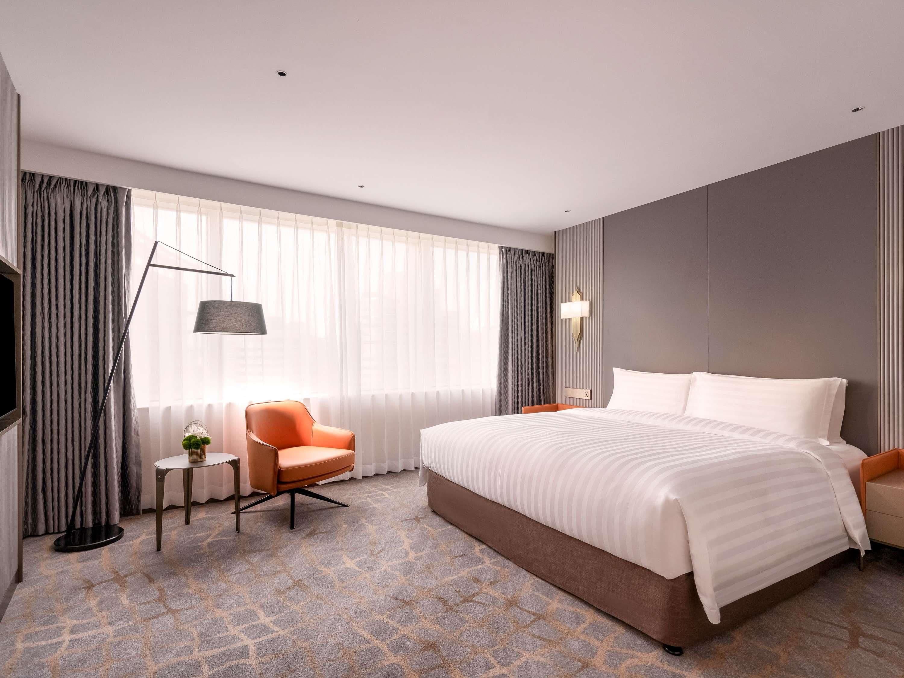Una habitación de hotel con una cama grande, una silla, una mesita y un televisor.