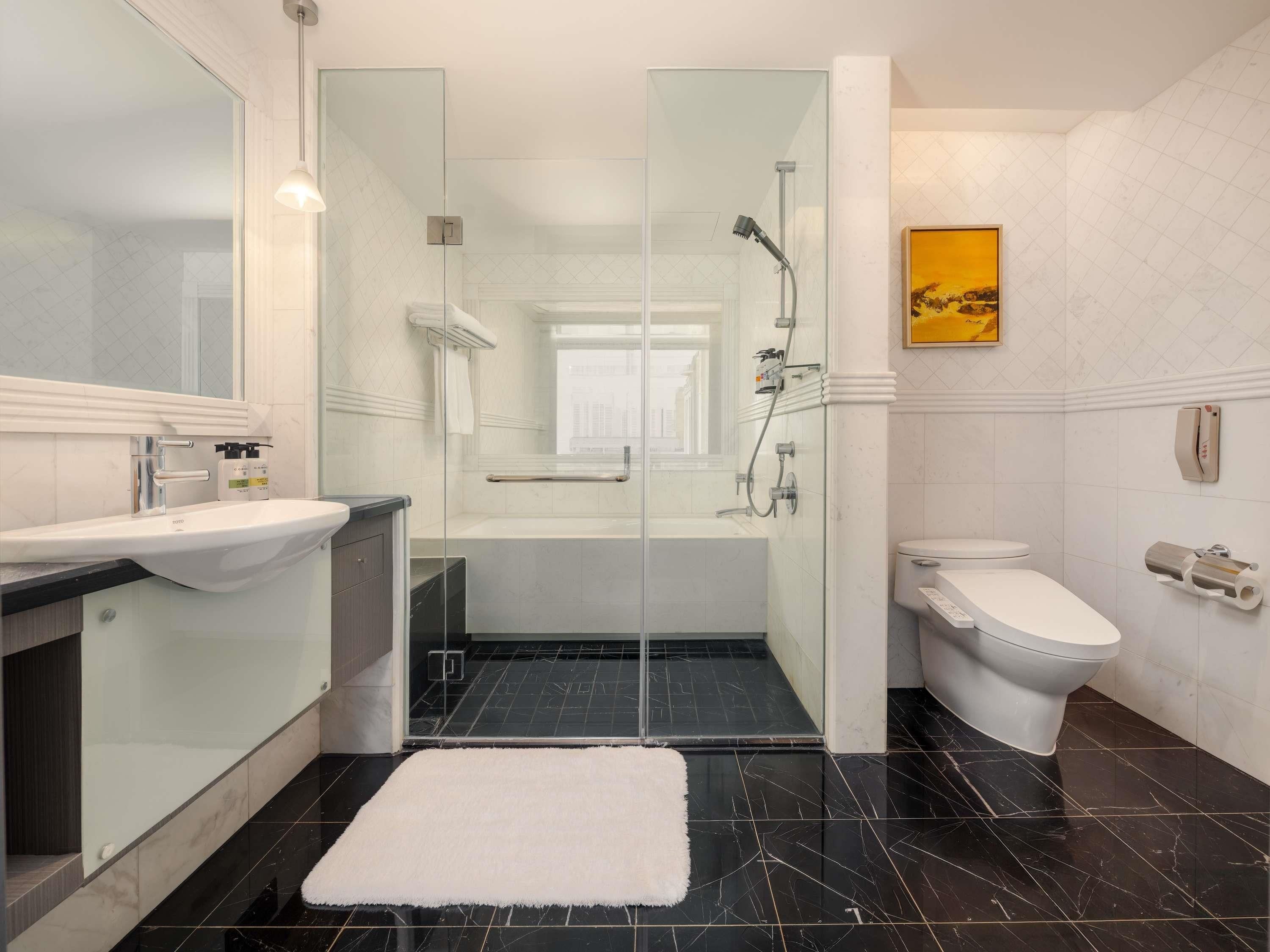 A modern bathroom with a glass-enclosed shower, a toilet, and a sink.