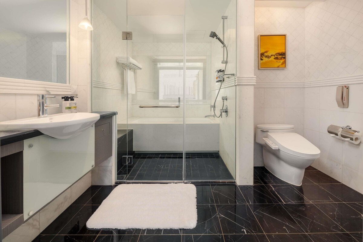 A modern bathroom with a glass-enclosed shower, a toilet, and a sink.