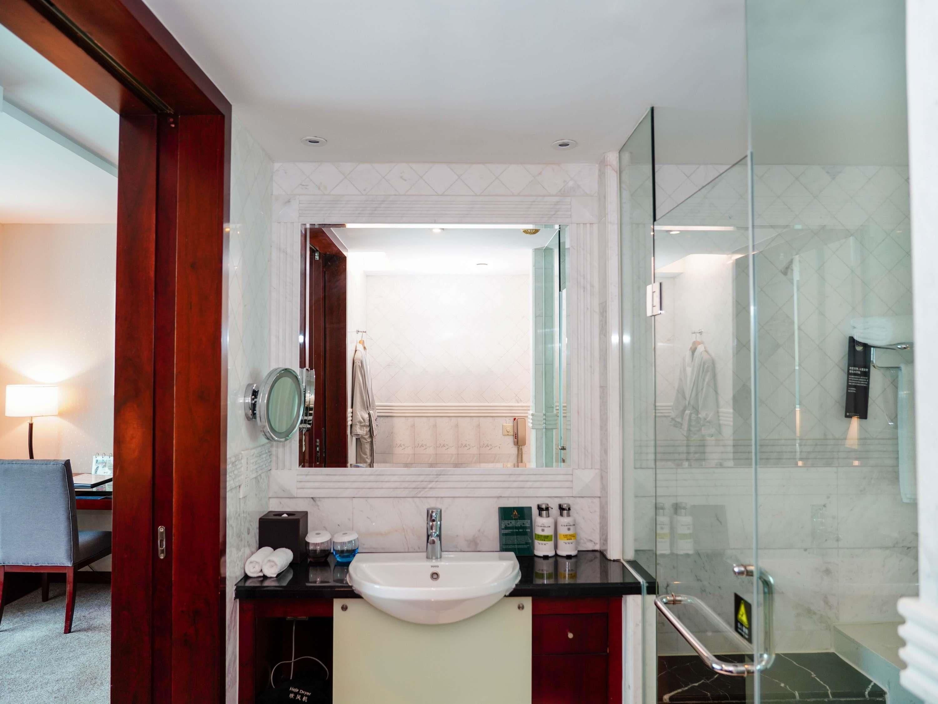 A modern bathroom with a sink, mirror, and glass shower enclosure.