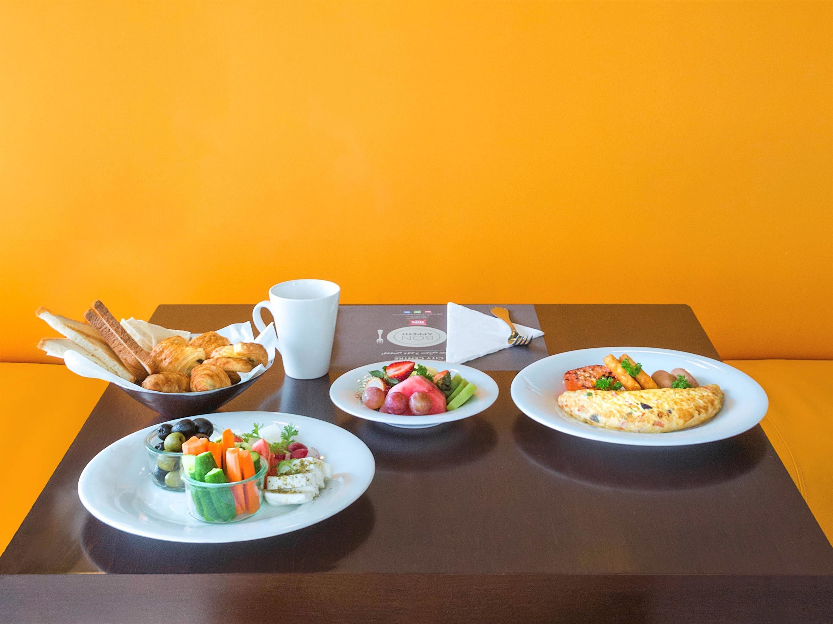 A table with breakfast items including croissants, a fruit salad, and an omelette.