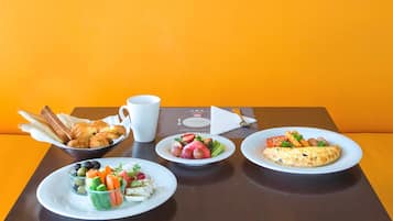 A table with breakfast items including croissants, a fruit salad, and an omelette.