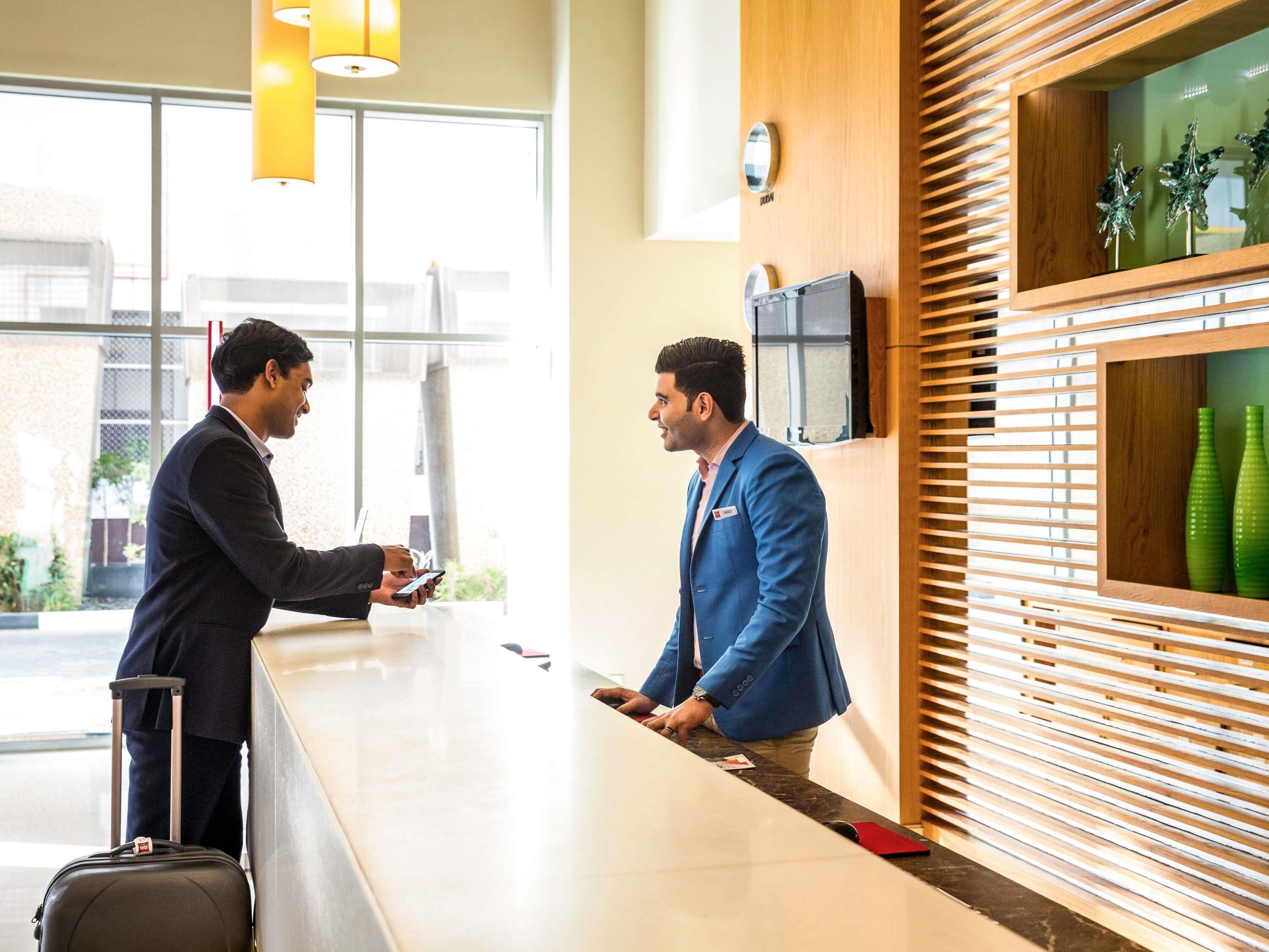 A reception desk with a modern design, featuring a wooden panel wall and a flat-screen TV mounted above it.