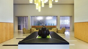 Um hall moderno com balcão de recepção, área de estar e um vaso grande sobre uma mesa.