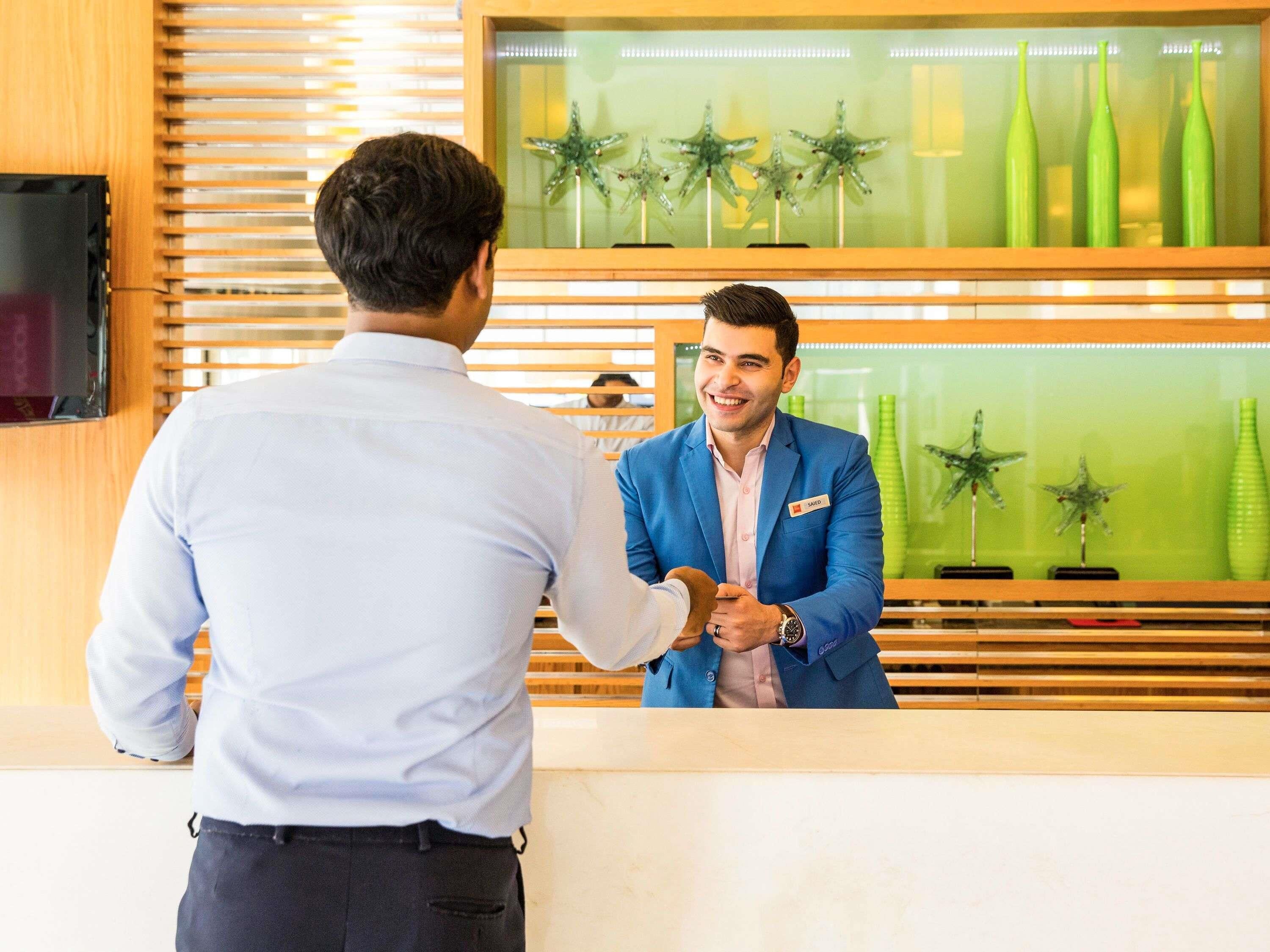 A reception area with a wooden counter, a television on the left, and decorative starfish on the glass wall.