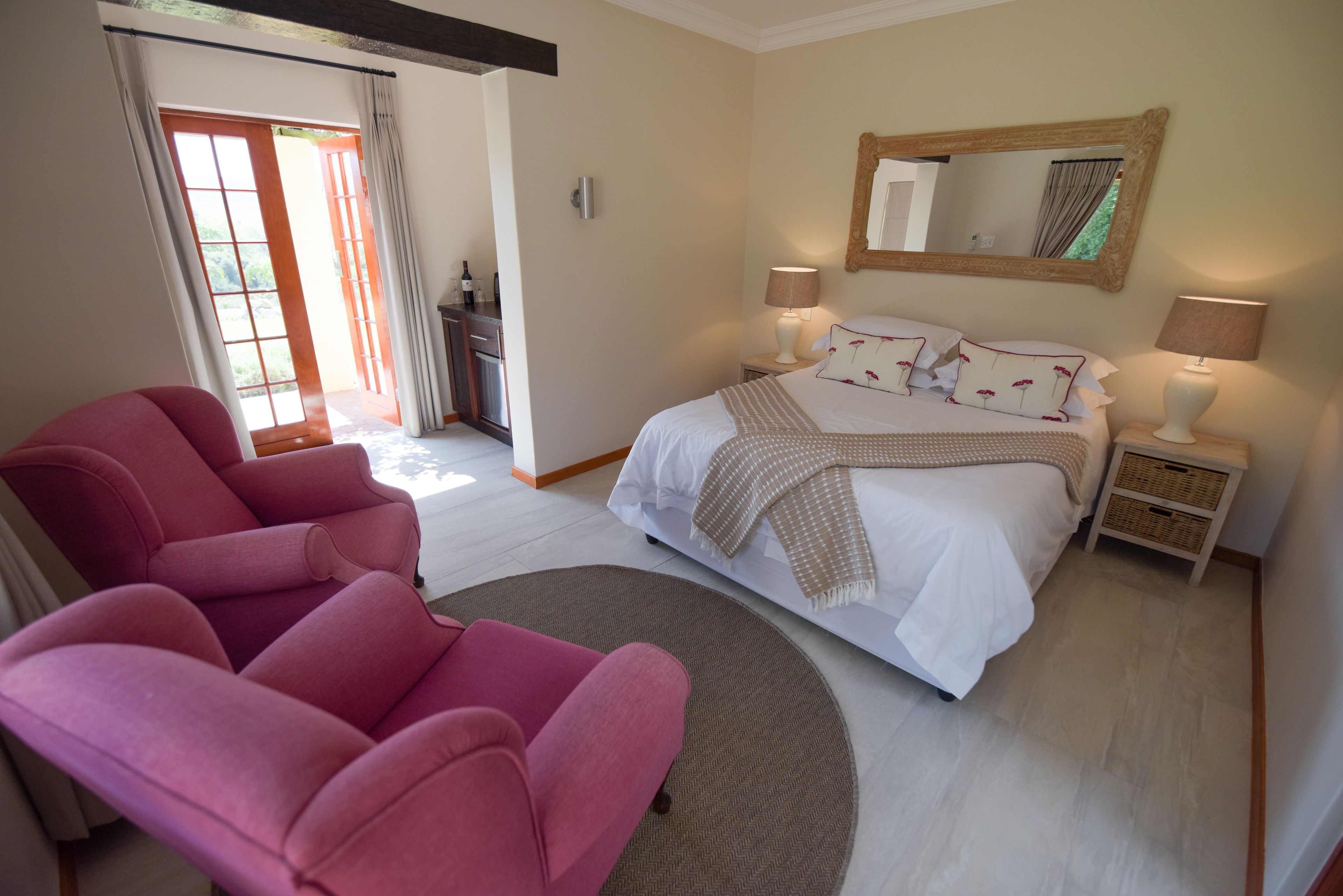 A bedroom with a bed, two bedside tables, a chair, a mirror, and a door leading to a balcony.
