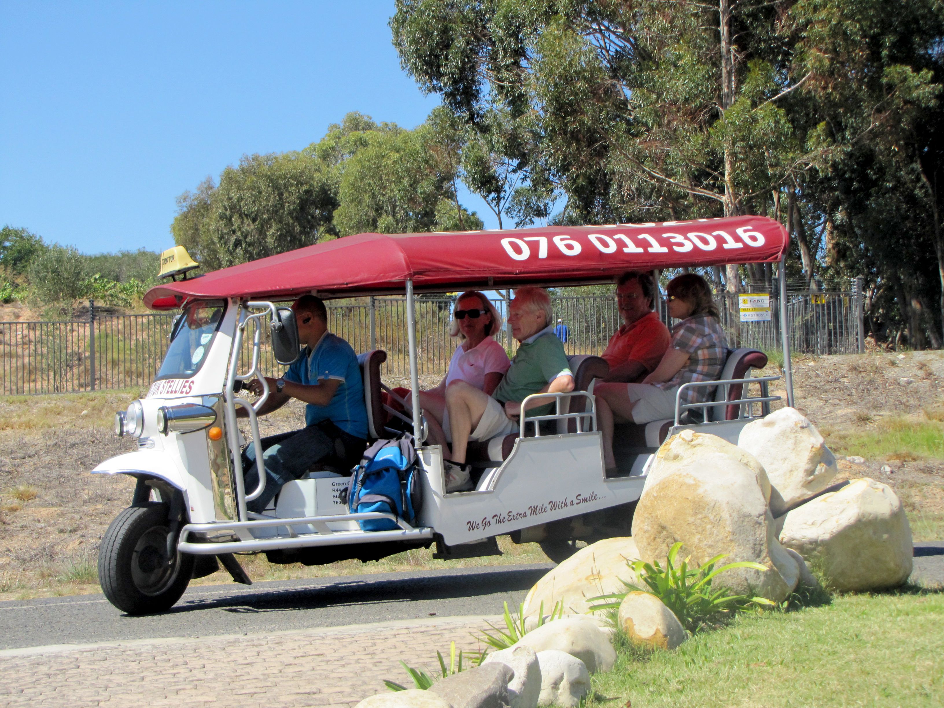A golf cart with a red canopy and a phone number on the side.