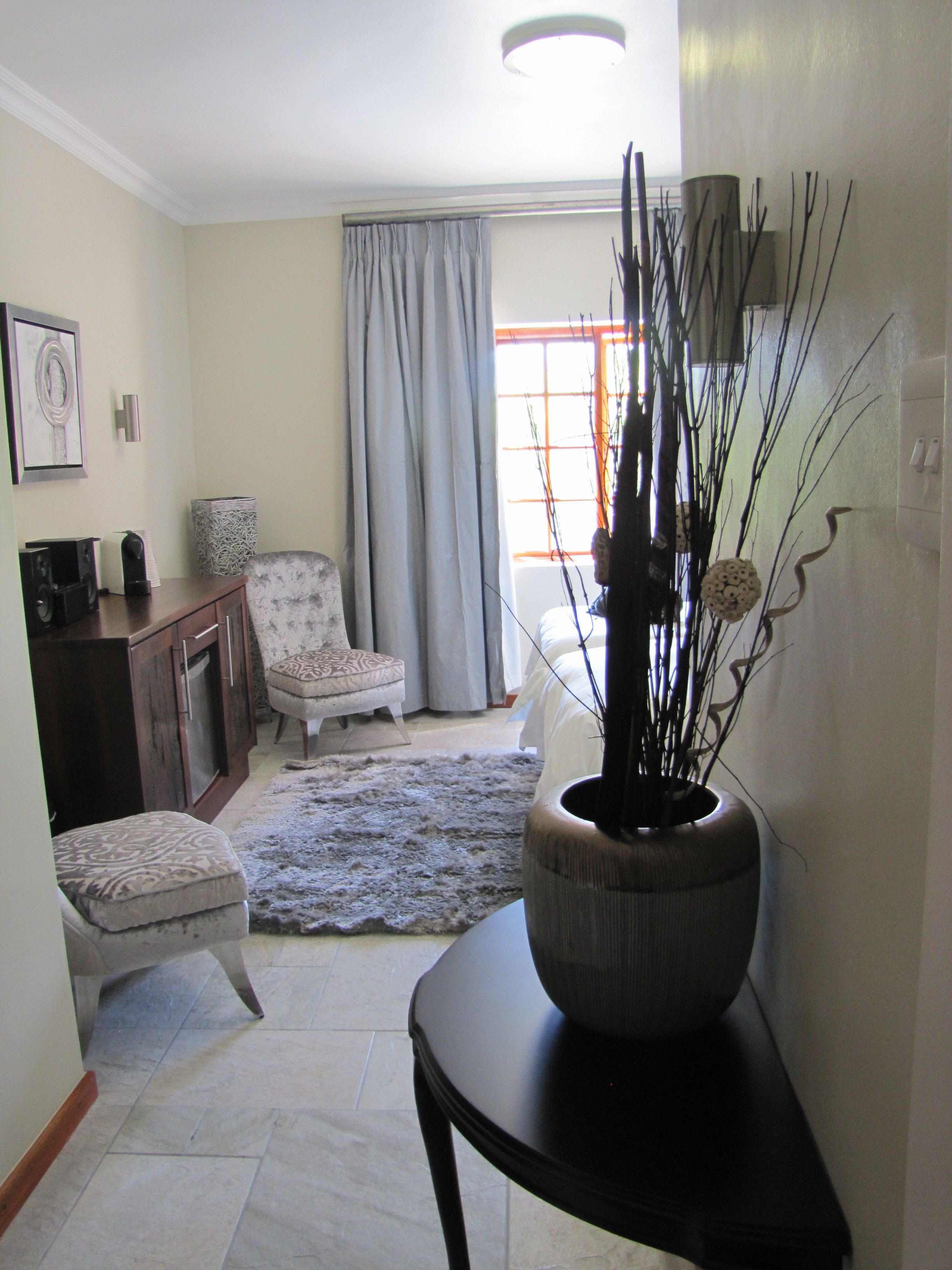 A living room with a sofa, a chair, a coffee table, a decorative vase, and a window with curtains.