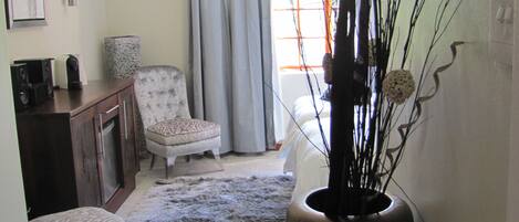 A living room with a sofa, a chair, a coffee table, a decorative vase, and a window with curtains.