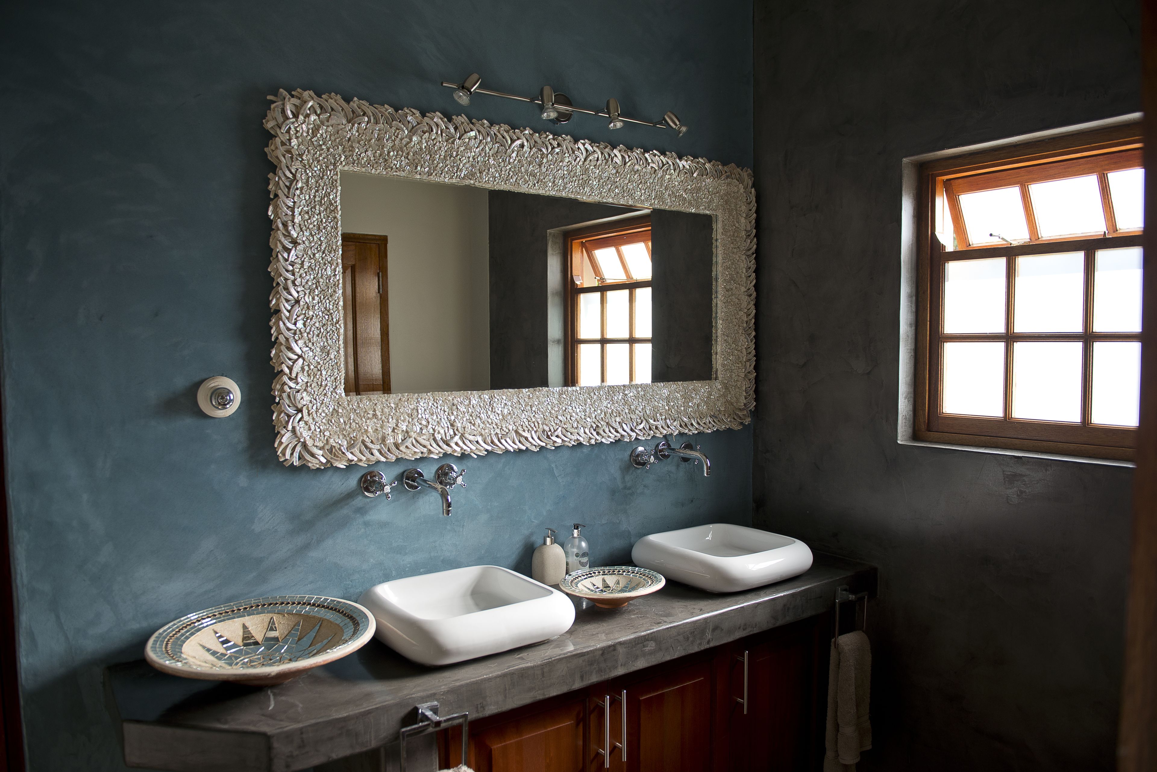 A bathroom with two sinks, a large ornate mirror, and a window with natural light.