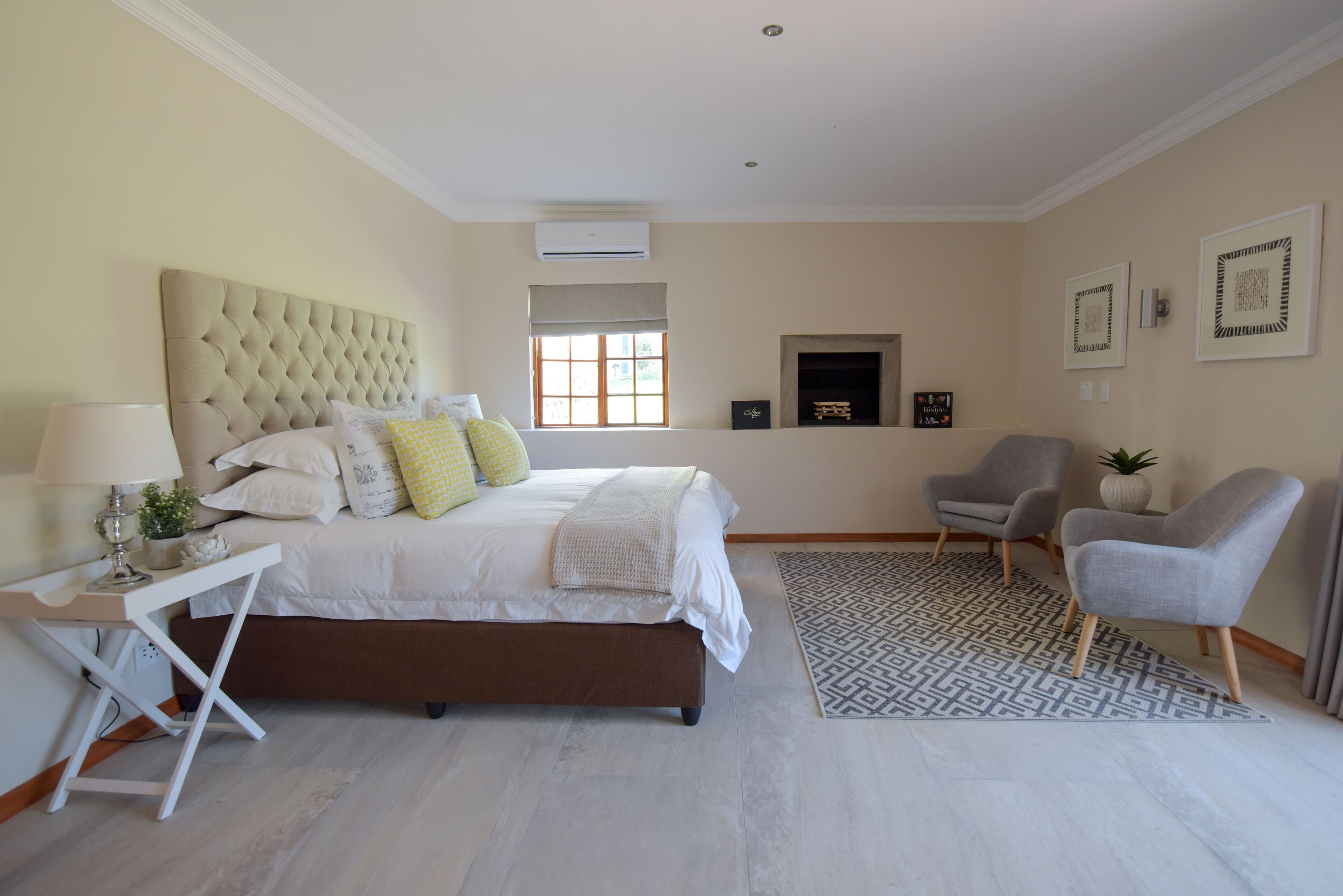 A bedroom with a bed, bedside table, lamp, and a fireplace.