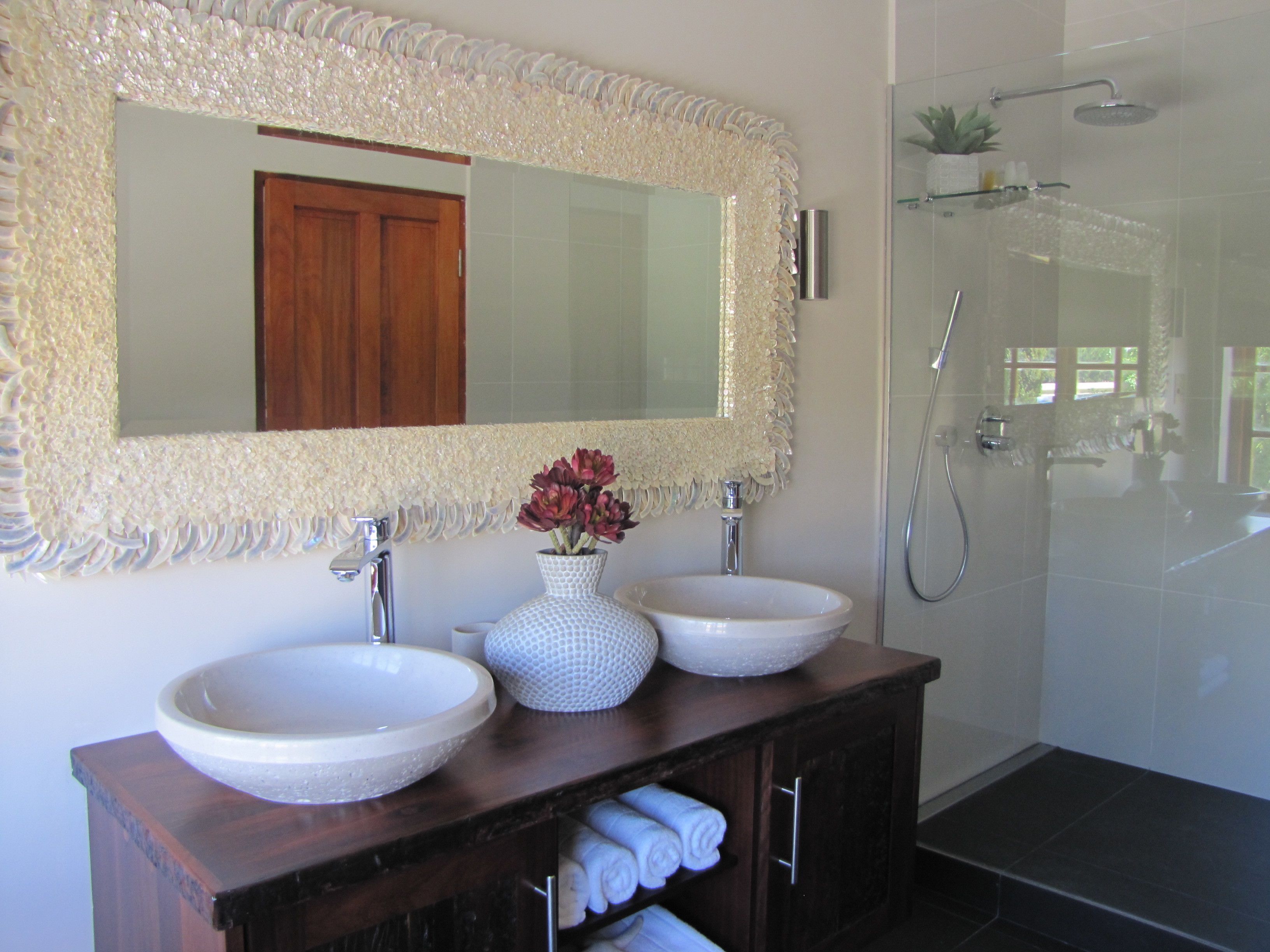 A bathroom with two sinks, a large mirror, and a shower.