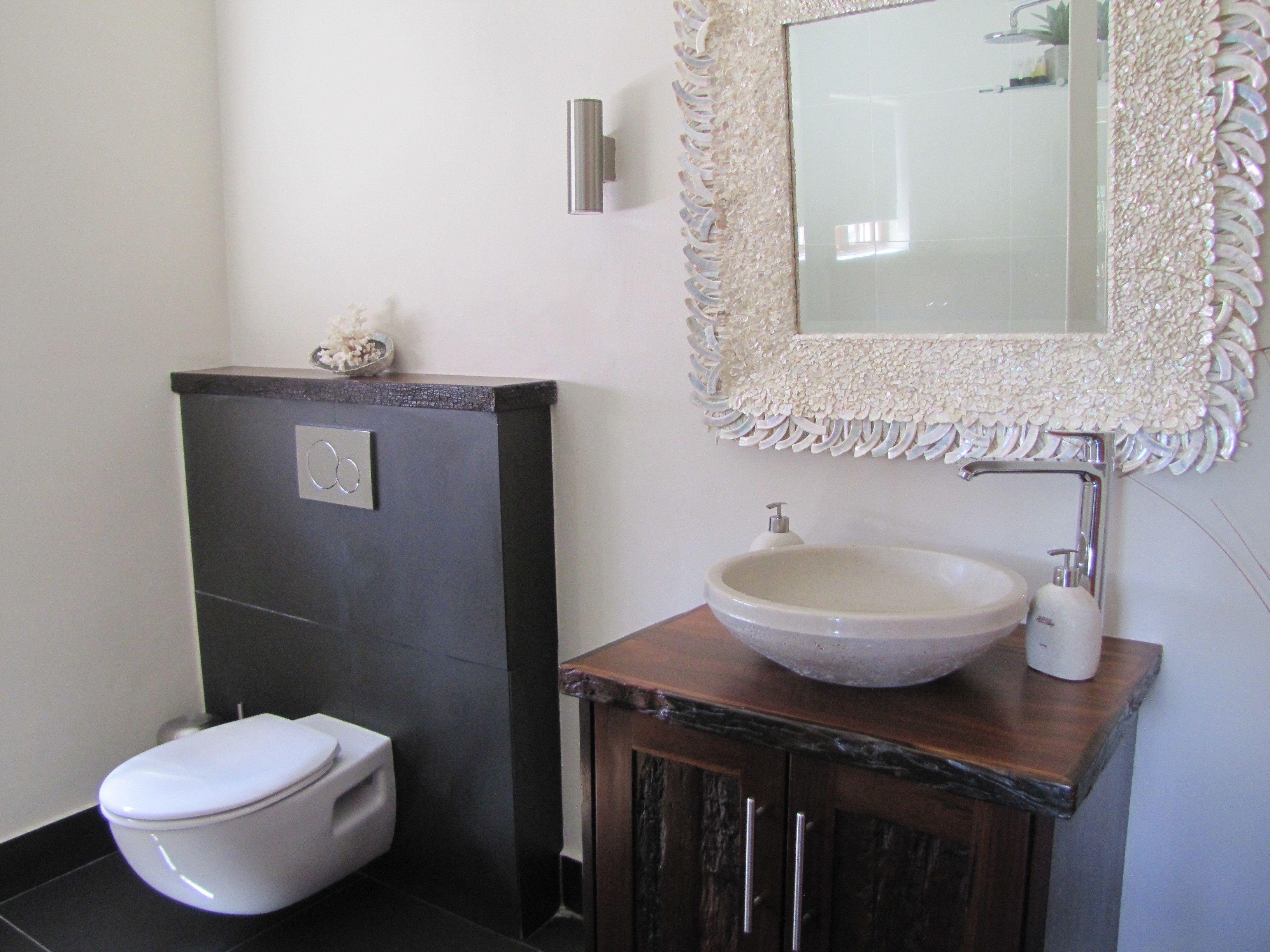 A bathroom with a toilet, a sink, and a mirror.