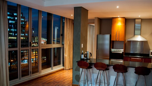 Una cucina moderna con una grande finestra, un piano cottura in acciaio inossidabile e un angolo bar con sgabelli.
