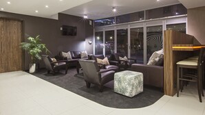 Una zona relax moderna con divani in pelle, un tavolino da caffè e un'ampia pianta in vaso.