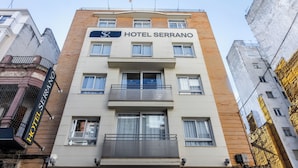 A multi-story hotel named Hotel Serrano with balconies and a signboard.